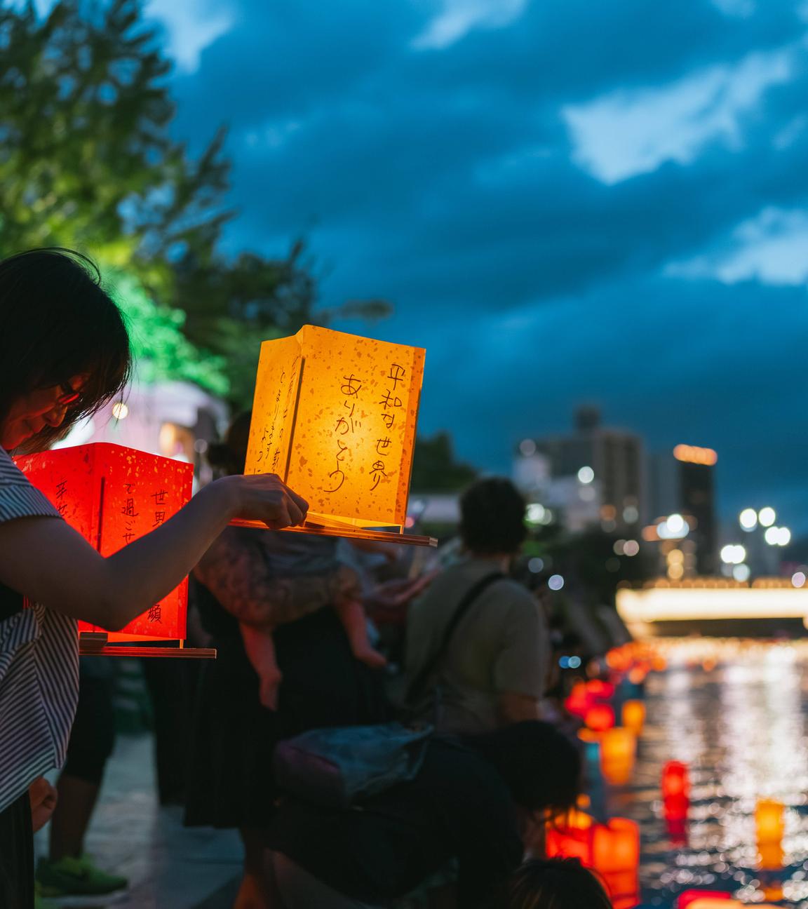 Eine Frau bereitet sich darauf vor, während des Laternenabends zum 80. Jahrestag des Atombombenabwurfs auf Hiroshima im Peace Memorial Park eine Laterne auf den Motoyasu-Fluss zu stellen