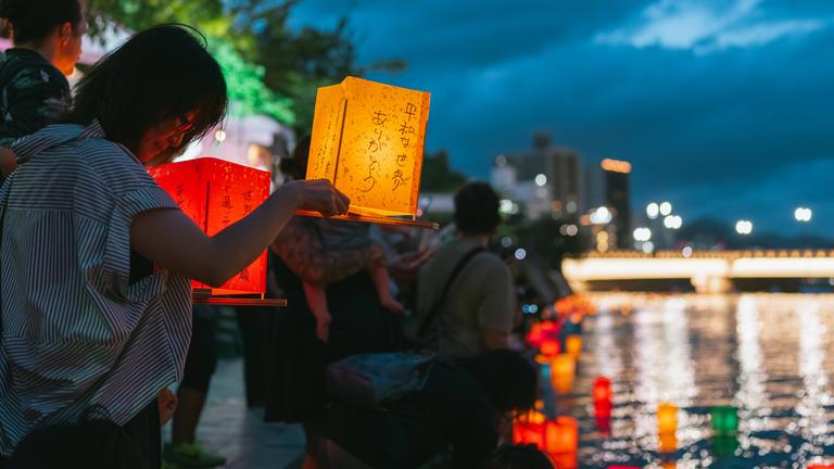 Eine Frau bereitet sich darauf vor, während des Laternenabends zum 80. Jahrestag des Atombombenabwurfs auf Hiroshima im Peace Memorial Park eine Laterne auf den Motoyasu-Fluss zu stellen