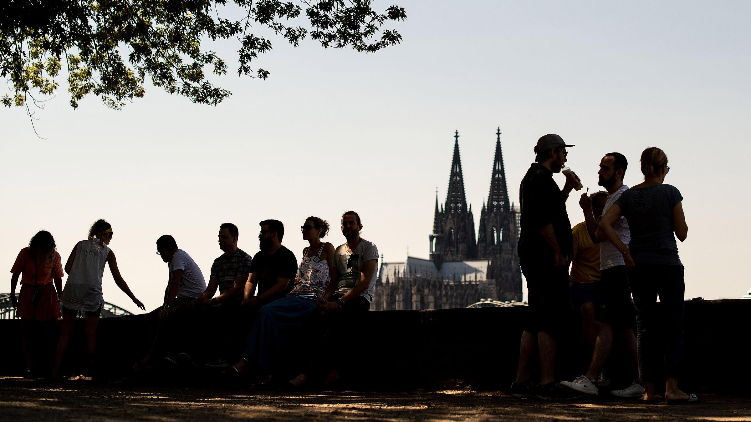 Menschen sitzen in der heissen Mittagszeit unter einem Baum im Schatten.