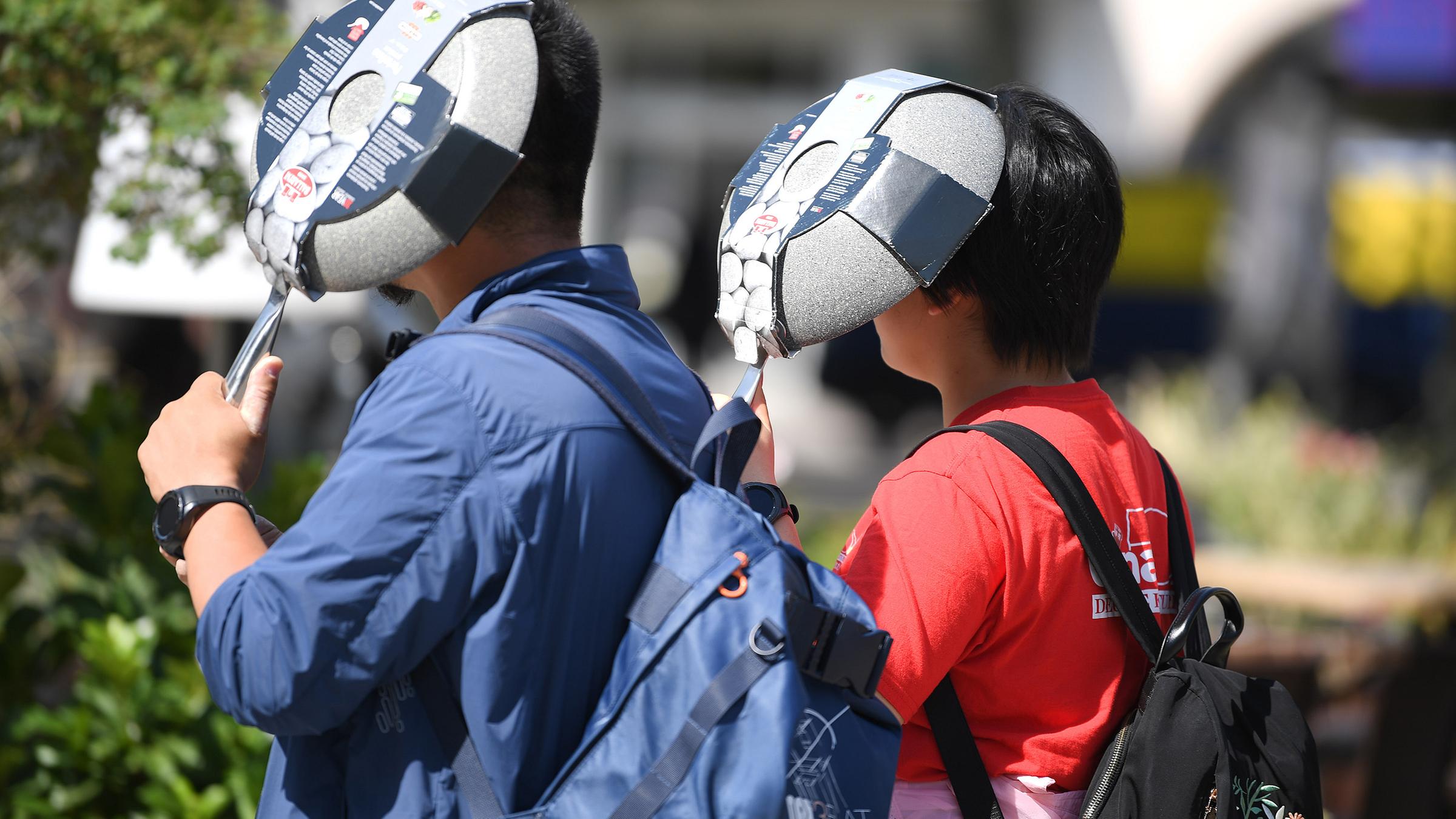 Mit neu gekauften Bratpfannen schützen Touristen ihre Köpfe vor der heissen Sonne.