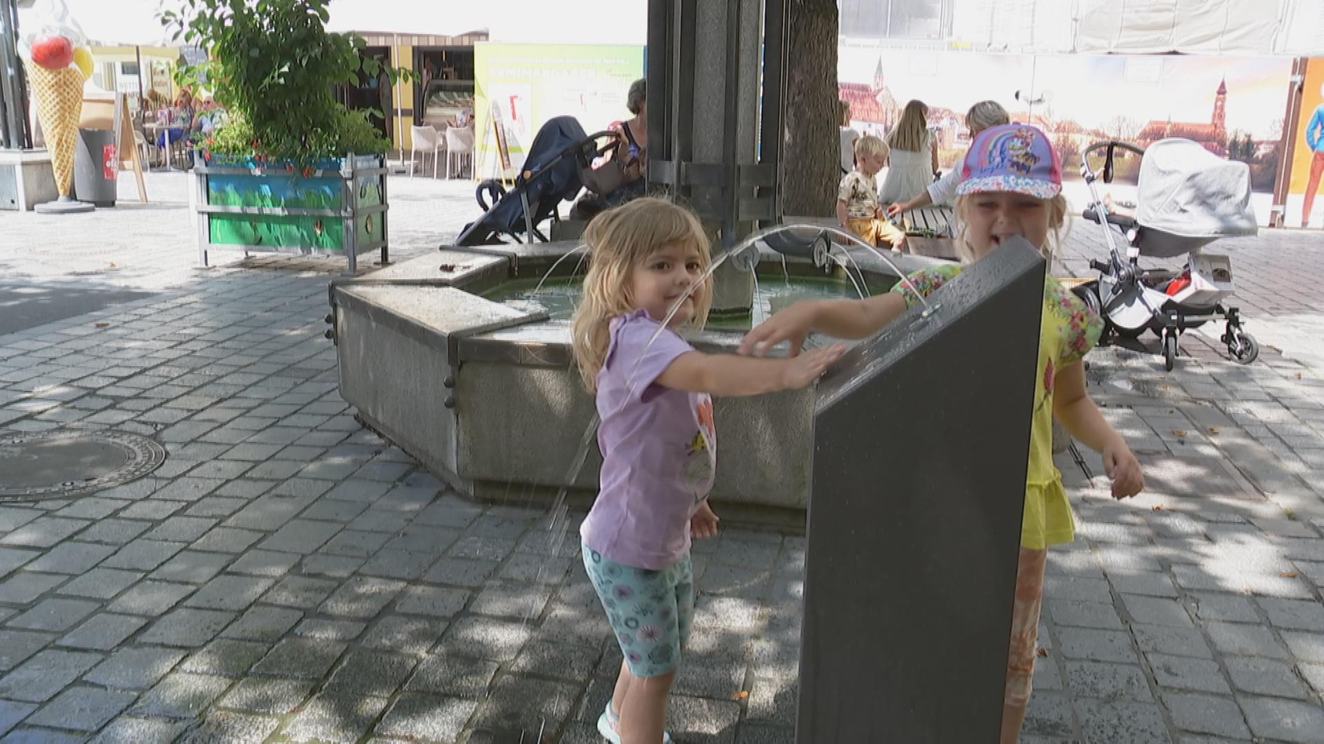Kind trinkt von Brunnen in der Innenstadt