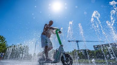 Tomas aus Berlin fährt mit seinem E-Scooter durch das Wasserspiel vor dem Kanzleramt.