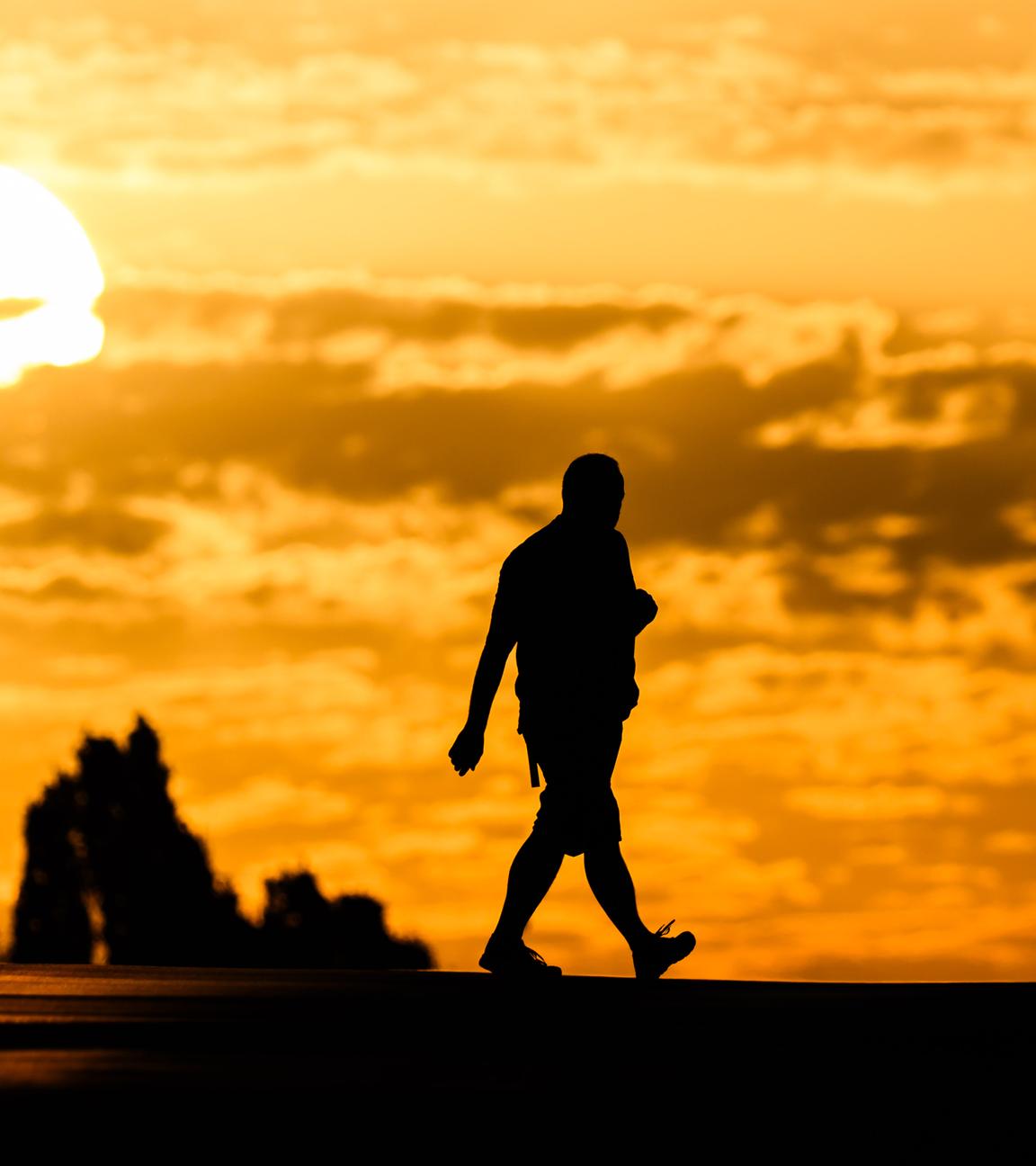 Symbolbild:  Ein Mann geht bei Sonnenaufgang über eine Straße in der Region Hannover. 