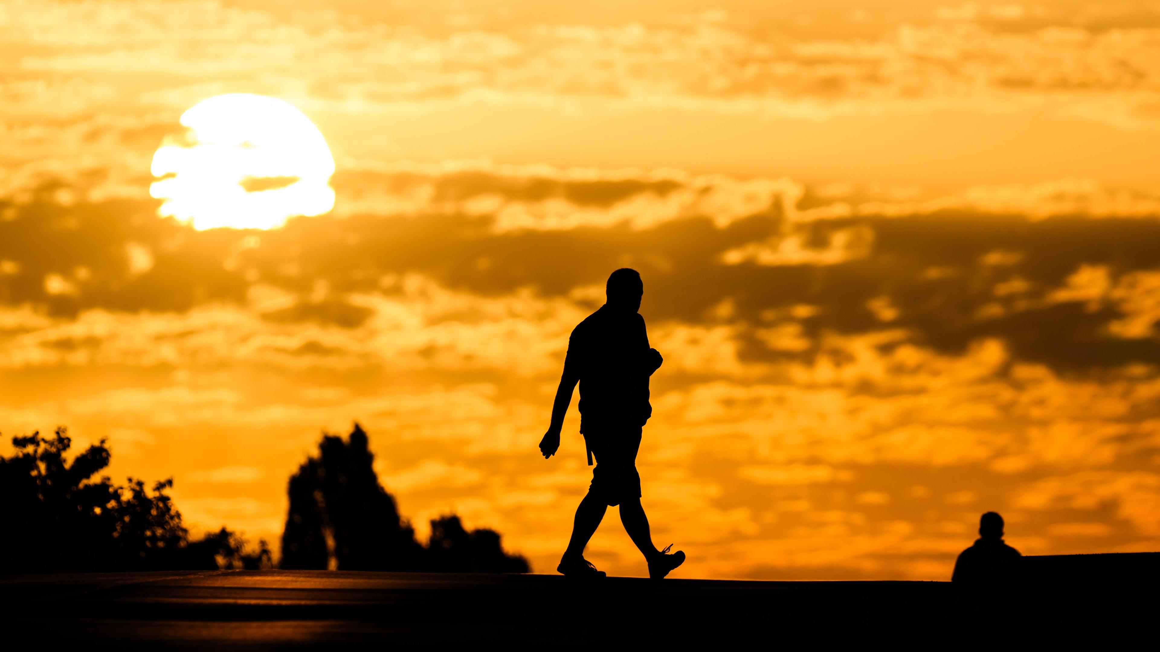 Symbolbild:  Ein Mann geht bei Sonnenaufgang über eine Straße in der Region Hannover. 