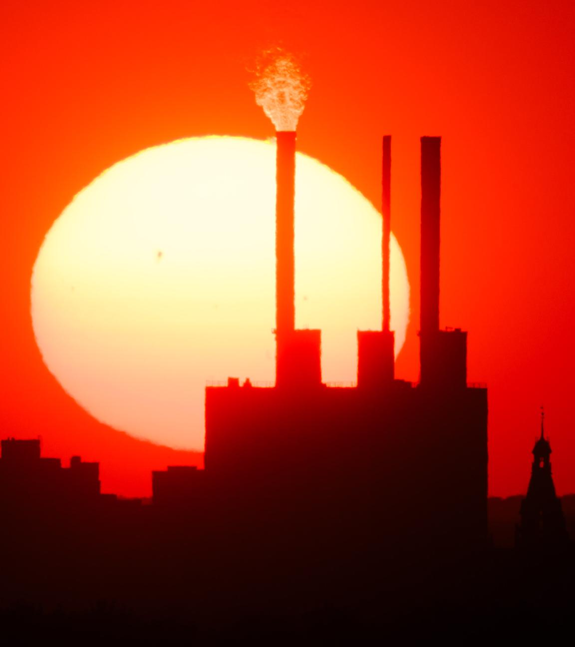 Die Sonne geht hinter dem Heizkraftwerk Linden und dem Neuen Rathaus unter. 