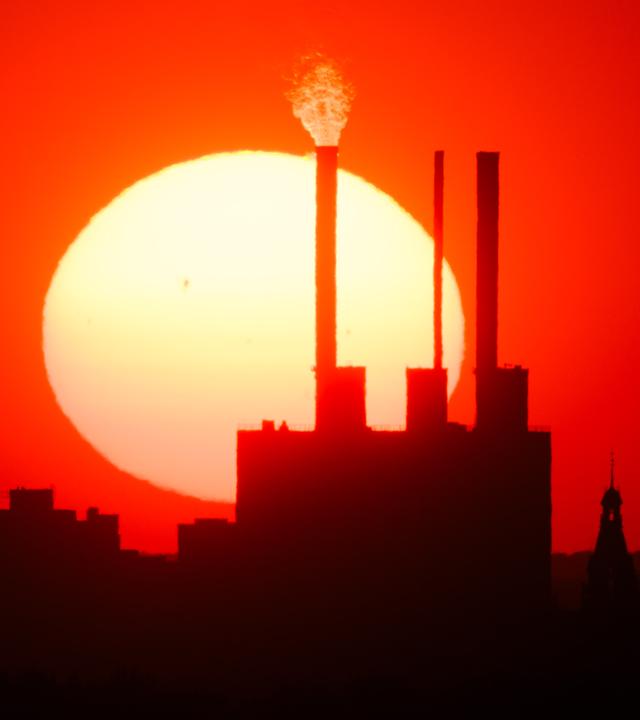 Die Sonne geht hinter dem Heizkraftwerk Linden und dem Neuen Rathaus unter. 