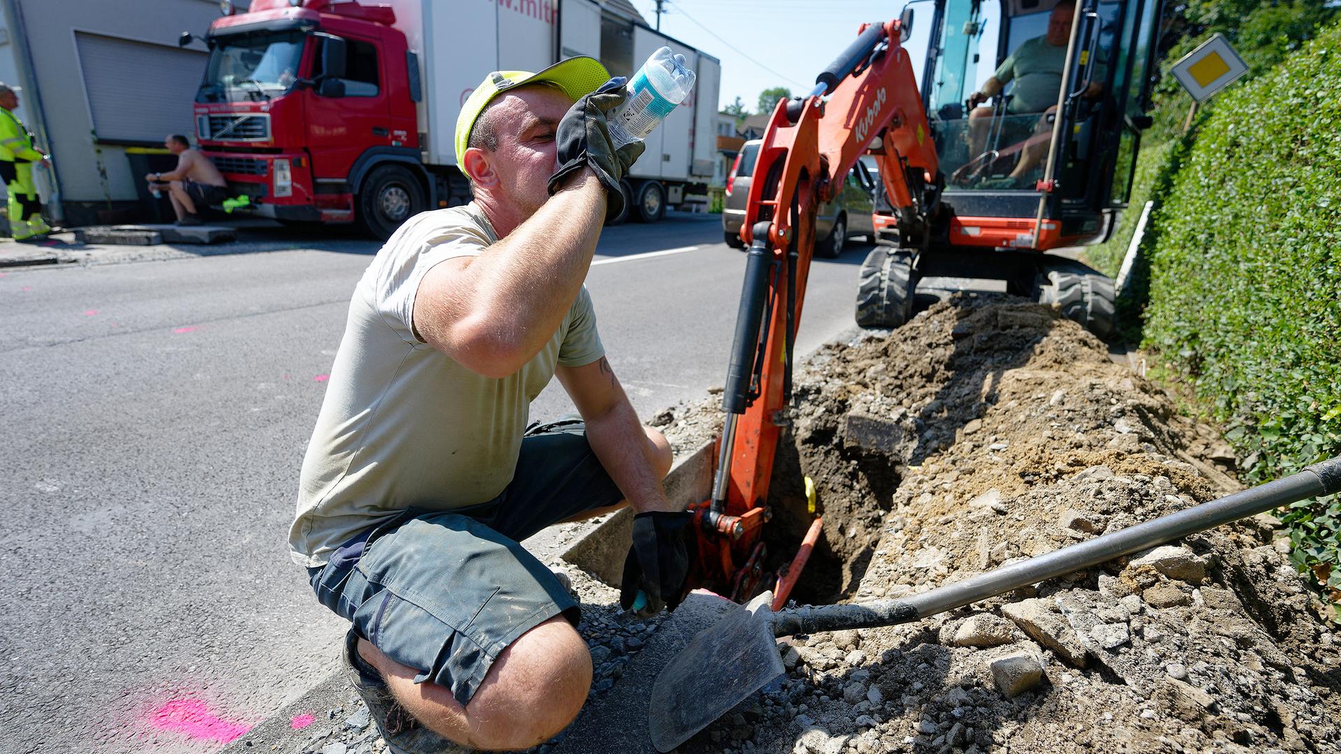 Arbeiter trinkt Wasser bei Mittagshitze
