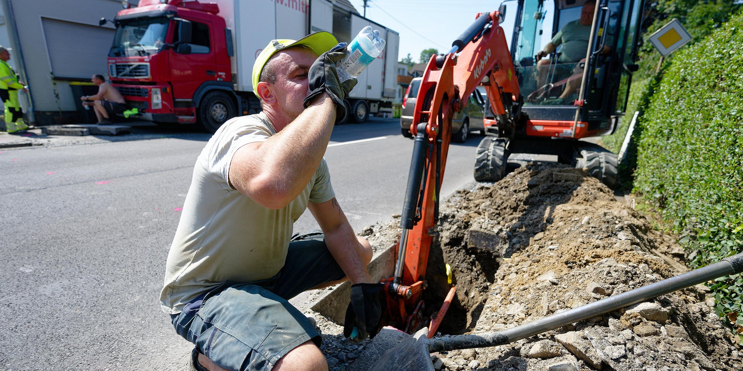 Arbeiter trinkt Wasser bei Mittagshitze