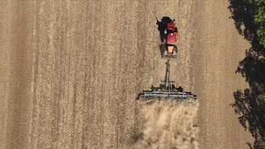 Traktor fährt über ein trockenes Feld.