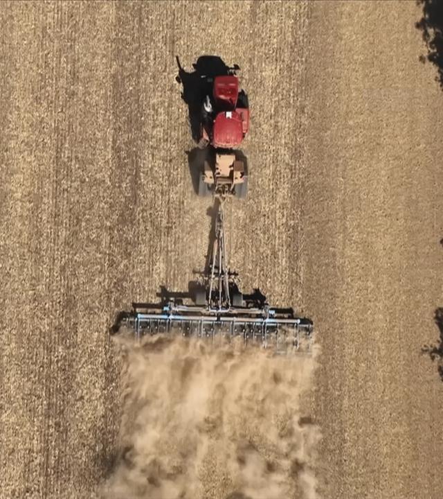 Traktor fährt über ein trockenes Feld.