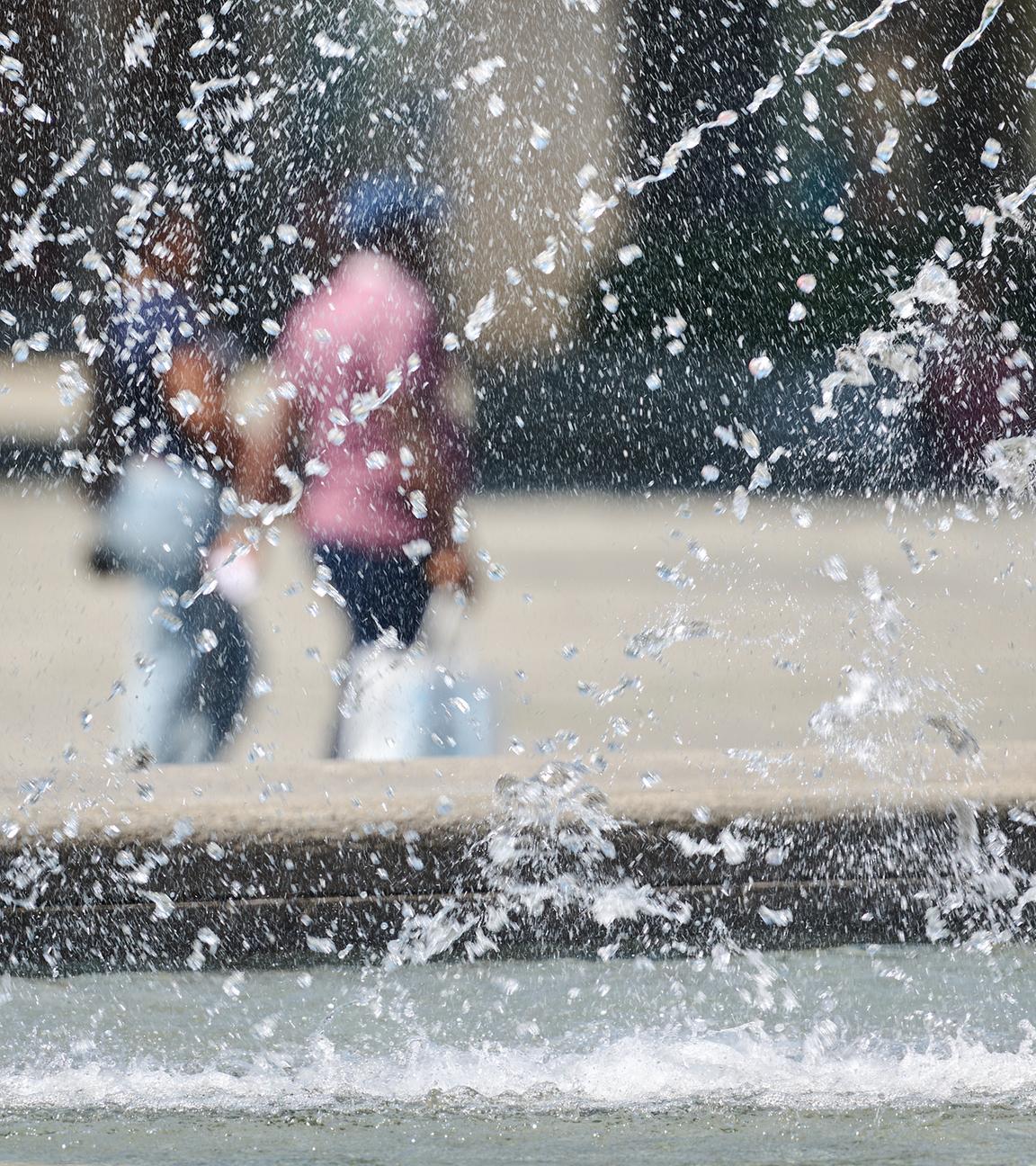 01.07.2025, Nordrhein-Westfalen, Dortmund: Passanten gehen hinter dem Brunnen auf dem Hansaplatz.