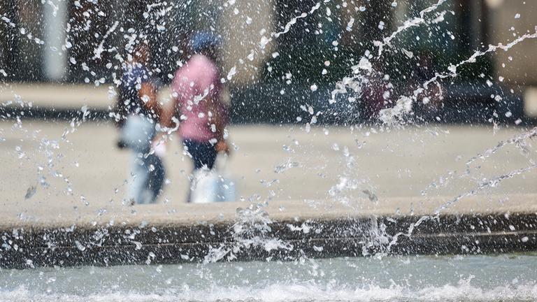 01.07.2025, Nordrhein-Westfalen, Dortmund: Passanten gehen hinter dem Brunnen auf dem Hansaplatz.