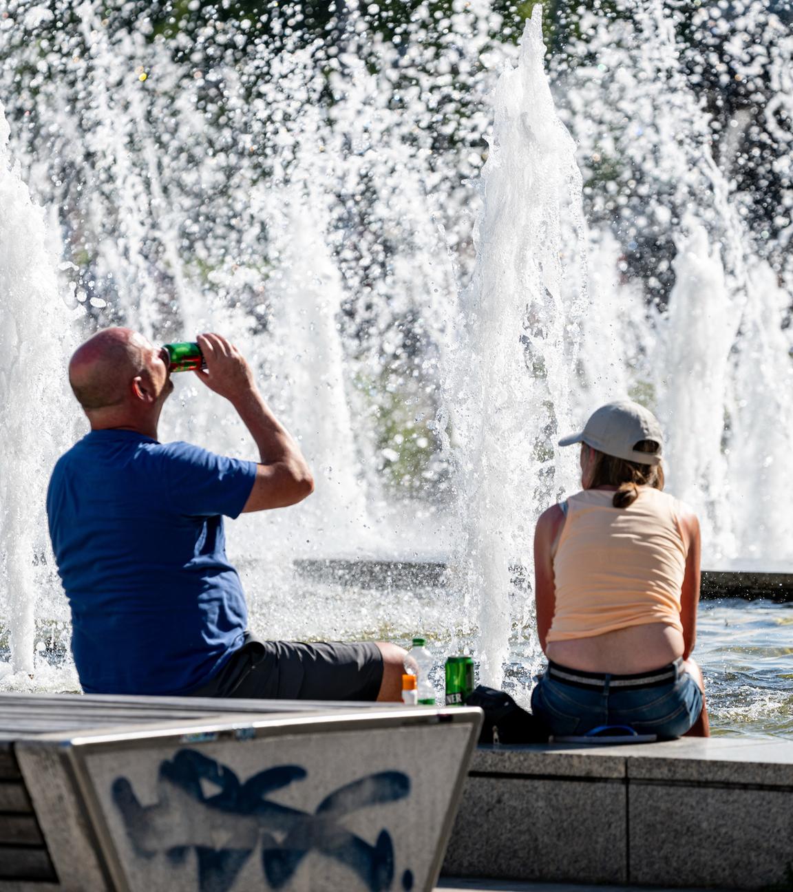 Berlin: Zwei Britische Touristen sitzen bei hohen Temperaturen am Alexanderplatz.