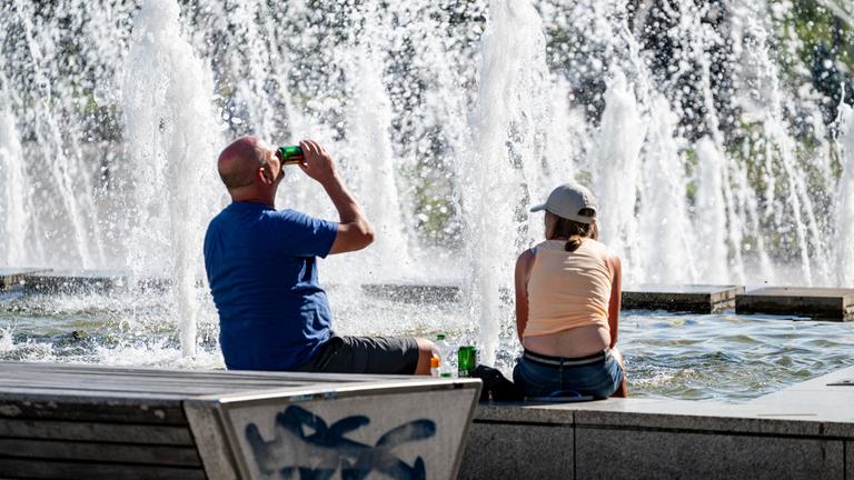 Berlin: Zwei Britische Touristen sitzen bei hohen Temperaturen am Alexanderplatz.