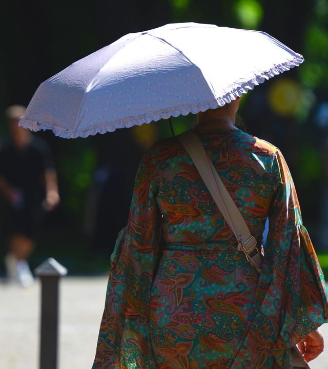 Eine Frau schützt sich mit einem Regenschirm vor der Sonne