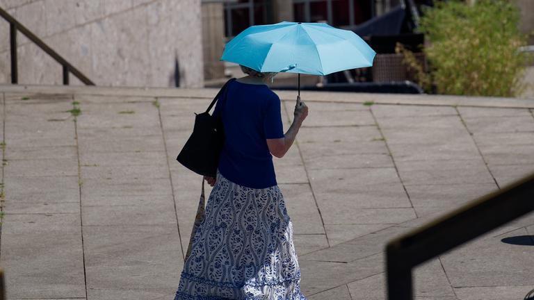 Köln: Eine Frau schützt sich mit einem Schirm vor der Sonne. 