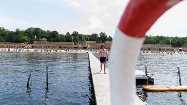 Ein Rettungsschwimmer geht auf dem Steg vom Strand zum Aussichtsturm im Strandbad Wannsee