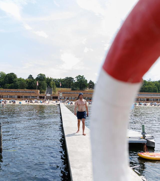 Ein Rettungsschwimmer geht auf dem Steg vom Strand zum Aussichtsturm im Strandbad Wannsee