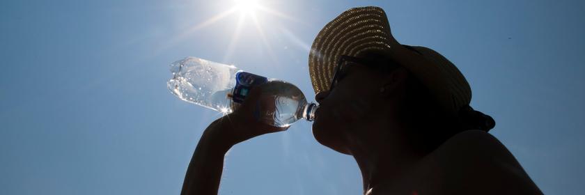Eine Frau mit Sonnenhut trinkt Wasser