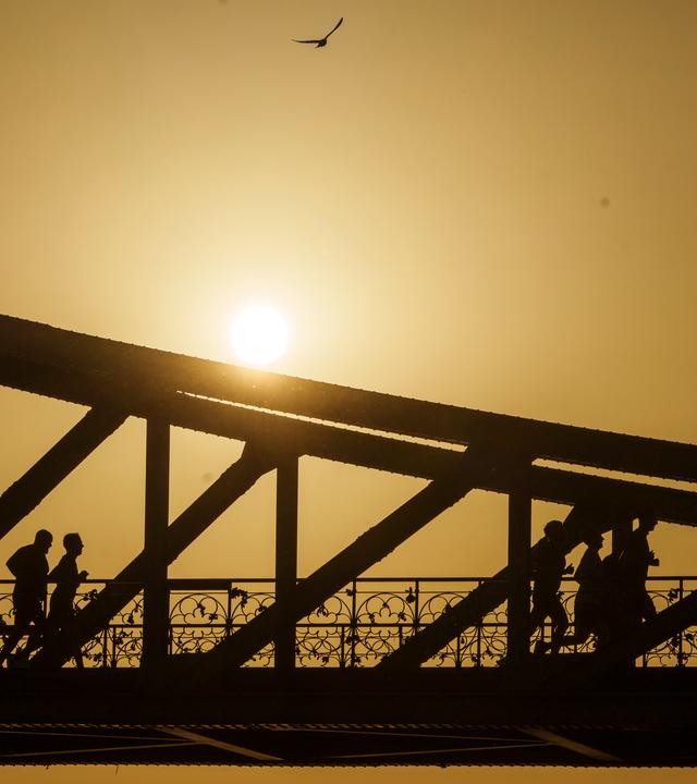 Eine Gruppe joggt bei Sonnenaufgang über den Eisernen Steg