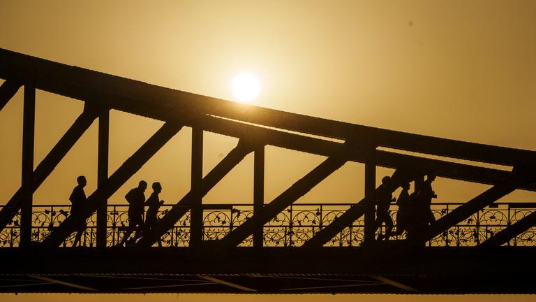 Eine Gruppe joggt bei Sonnenaufgang über den Eisernen Steg