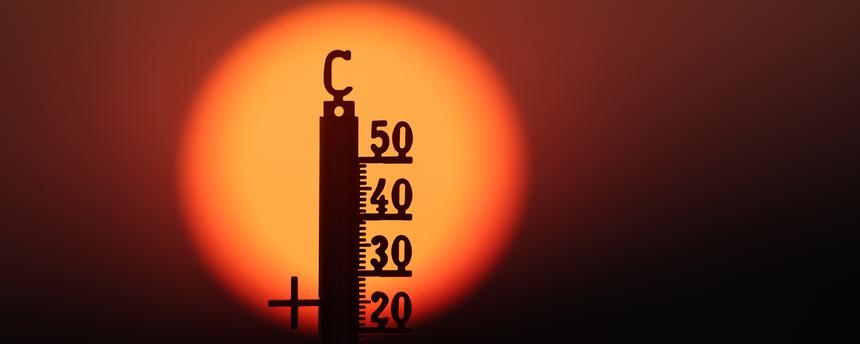 Hinter einem Thermometer geht am Morgen die Sonne auf