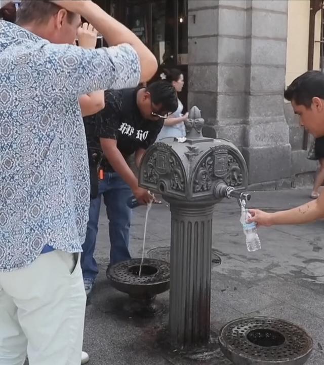 Menschen stehen in Rom an einem Brunnen und füllen sich Wasser ab.