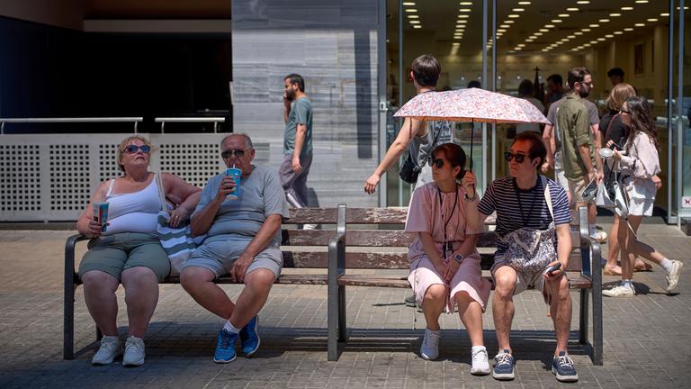 Ein Paar schützt sich an einem heißen Tag in Barcelona, ​​Spanien, am Montag, den 30. Juni 2025, mit einem Regenschirm vor der Sonne.