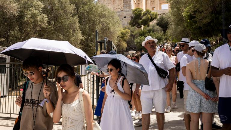 Touristen verlassen die Akropolis, die von 12:00 bis 17:00 Uhr wegen der Hitze geschlossen ist.