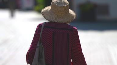 Eine Frau schützt sich mit einem Sonnenhut vor der Sonne.