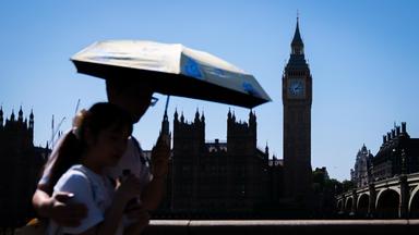London: Touristen schützen sich vor dem heißen Wetter unter einem Regenschirm auf der Westminster Bridge im Zentrum Londons