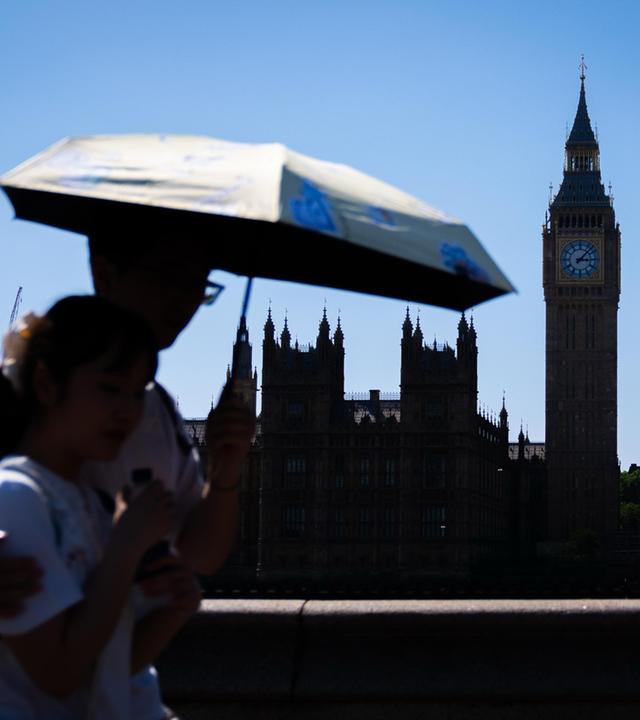 London: Touristen schützen sich vor dem heißen Wetter unter einem Regenschirm auf der Westminster Bridge im Zentrum Londons