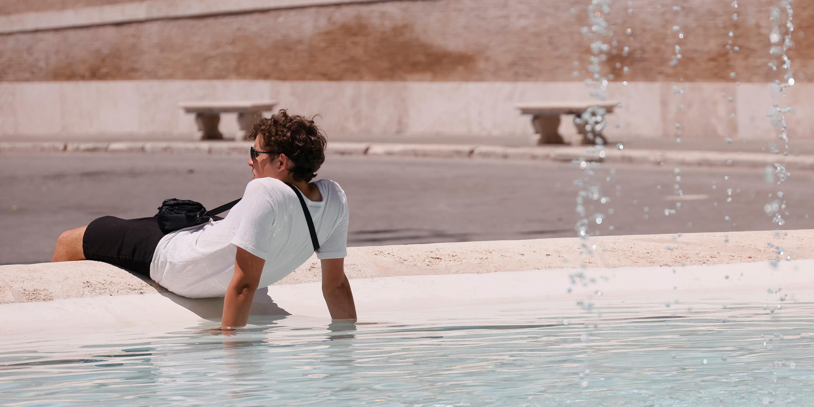 Ein Tourist kühlt sich am 29.06.2025 in einem Brunnen an der Piazza del Popolo in Rom ab.