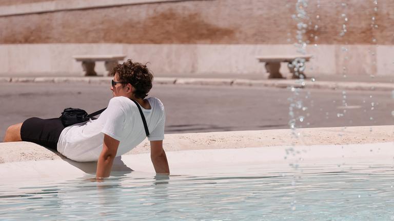 Ein Tourist kühlt sich am 29.06.2025 in einem Brunnen an der Piazza del Popolo in Rom ab.