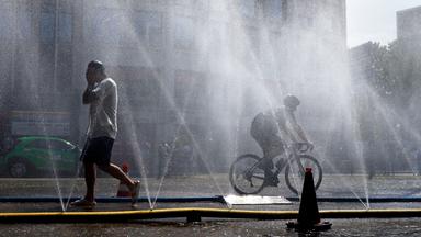 Passanten erfrischen sich an Wasserfontänen, die von der Stadt Köln im Rahmen der Hitzeaktion "Cooling Cologne" auf dem Rudolfplatz ausgelegt wurden.