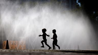Passanten erfrischen sich an Wasserfontänen, die von der Stadt Köln im Rahmen der Hitzeaktion 'Cooling Cologne' auf dem Rudolfplatz ausgelegt wurden. 