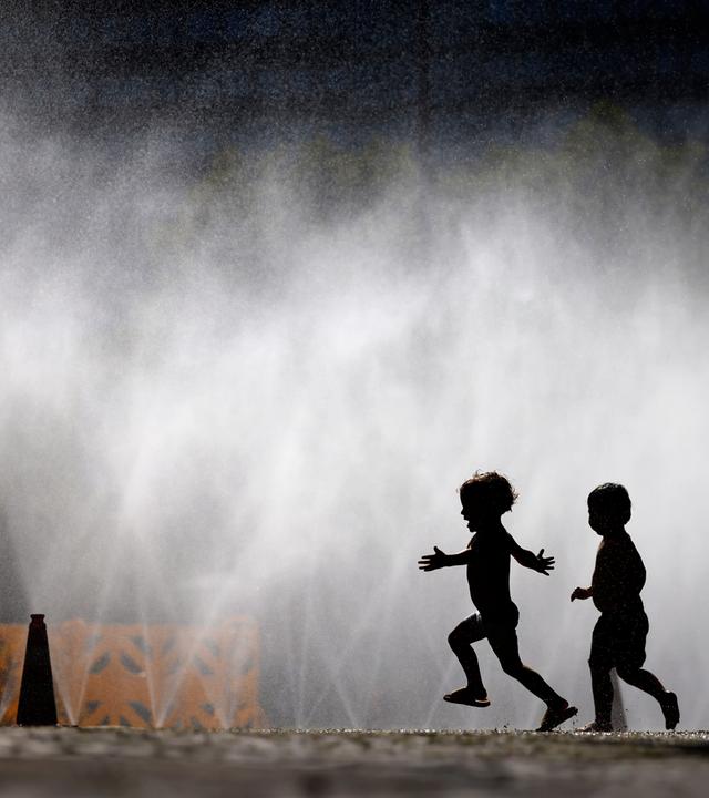 Passanten erfrischen sich an Wasserfontänen, die von der Stadt Köln im Rahmen der Hitzeaktion 'Cooling Cologne' auf dem Rudolfplatz ausgelegt wurden. 