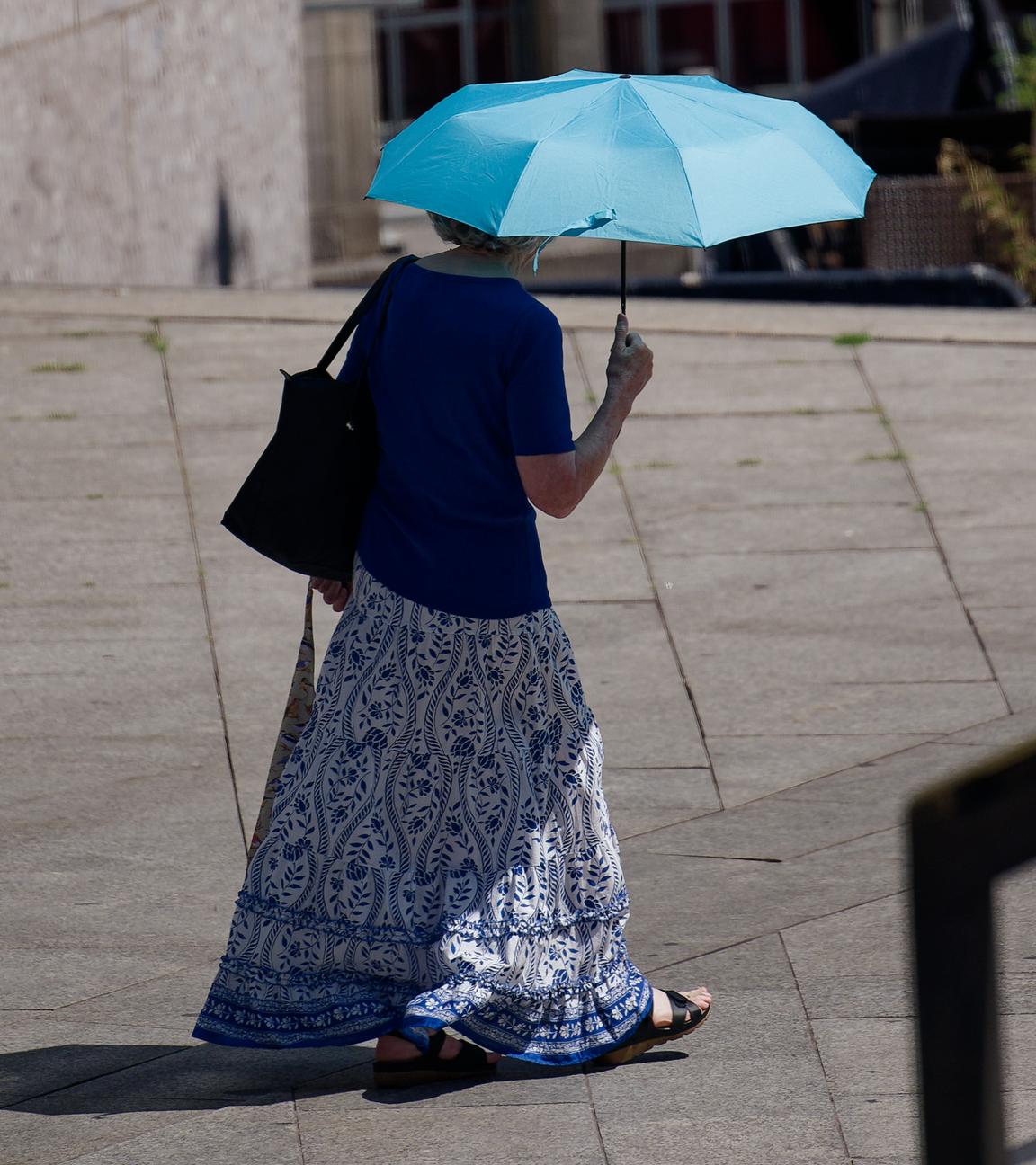Eine Frau schützt sich mit einem Schirm vor der Sonne.