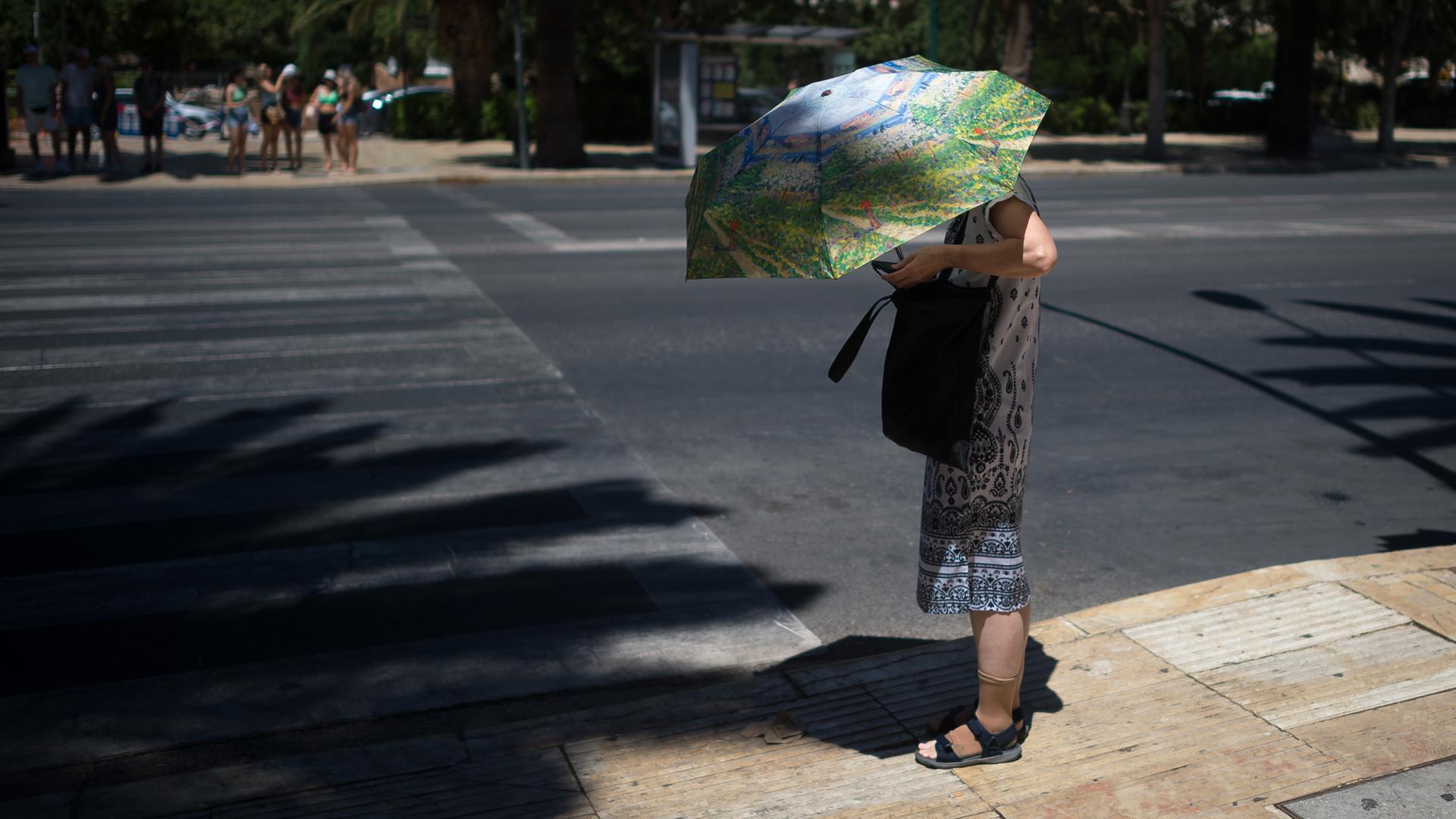 Archiv: Eine Touristin benutzt einen Regenschirm, um sich an einem heißen Sommertag in Málaga, Spanien, am 03.08.2023 vor der Sonne zu schützen.