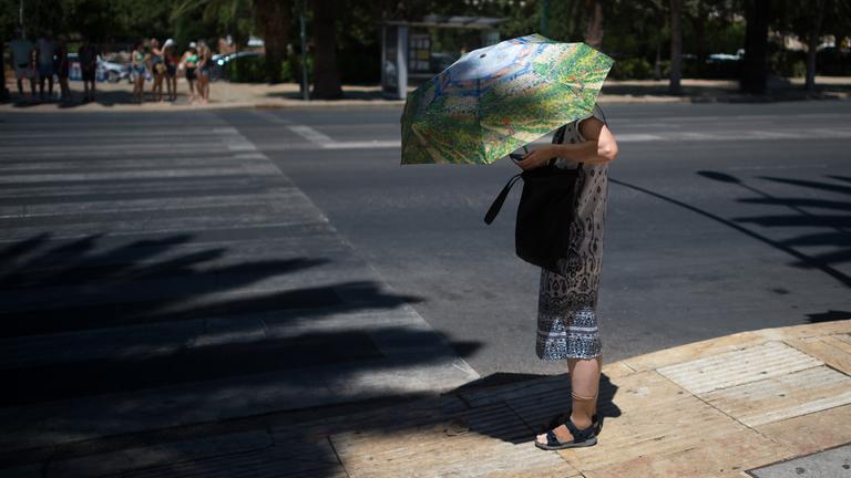 Archiv: Eine Touristin benutzt einen Regenschirm, um sich an einem heißen Sommertag in Málaga, Spanien, am 03.08.2023 vor der Sonne zu schützen.