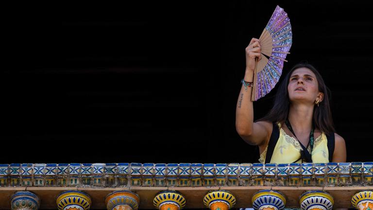 Eine Frau kühlt sich während einer Hitzewelle in Sevilla mit einem Ventilator ab.