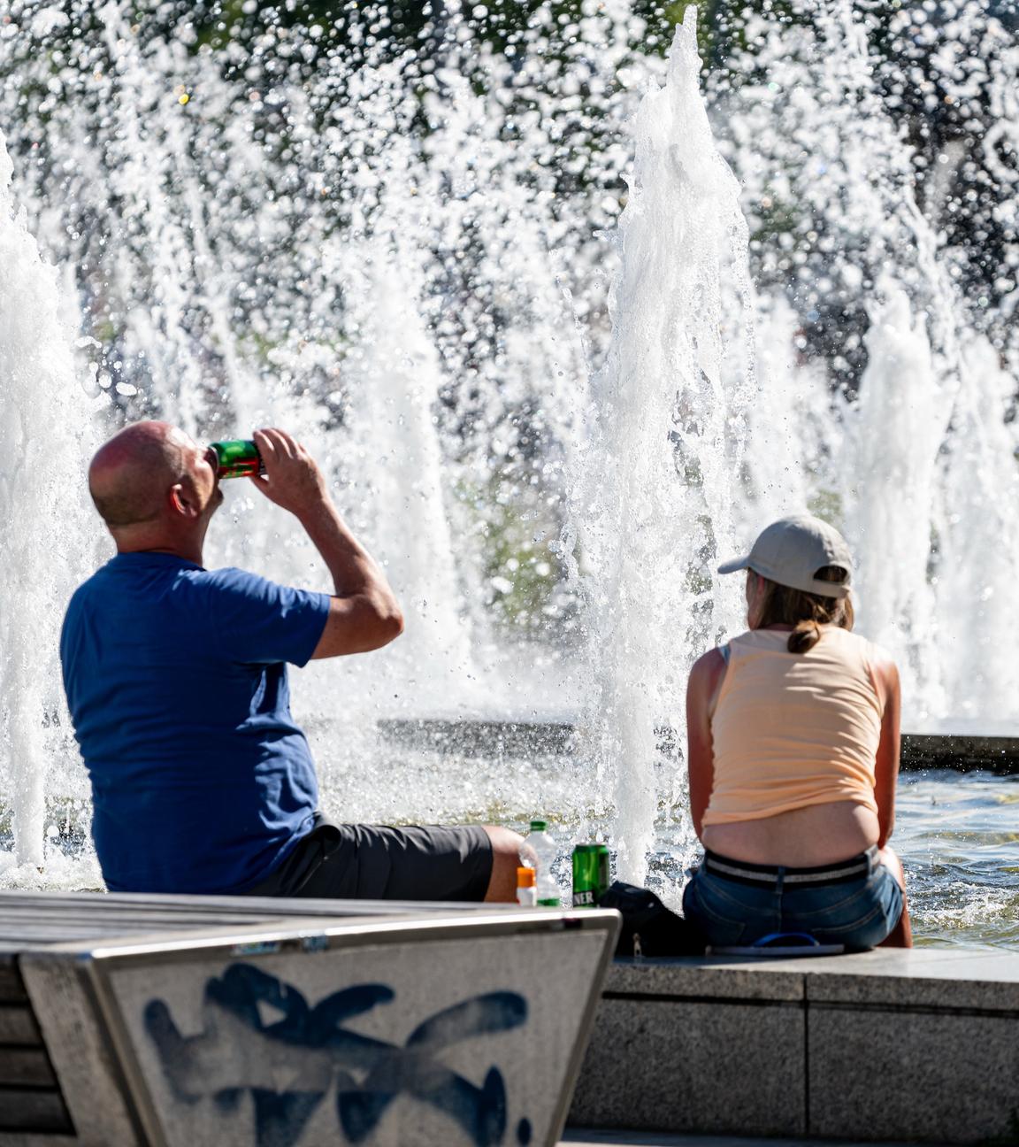 Zwei Britische Touristen sitzen bei hohen Temperaturen am Alexanderplatz.
