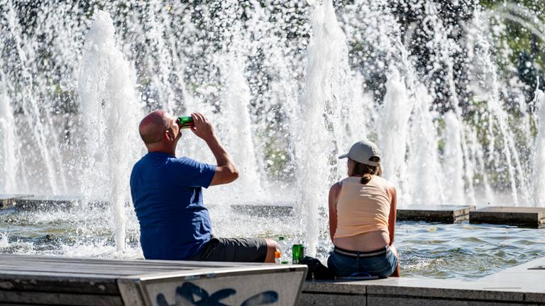Zwei Britische Touristen sitzen bei hohen Temperaturen am Alexanderplatz.