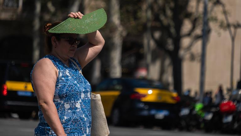 9. August 2024, Barcelona, Katalonien, Spanien: Eine Frau schützt sich mit einem Ventilator vor der Sonne, während sie durch eine der Einkaufsstraßen im Stadtzentrum läuft. 