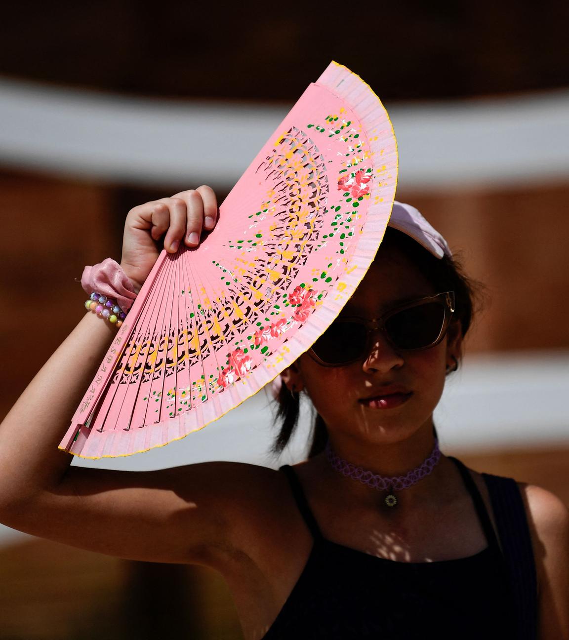 Eine Frau schützt sich mit einem Fächer vor der Sonne in Sevilla, Spanien.