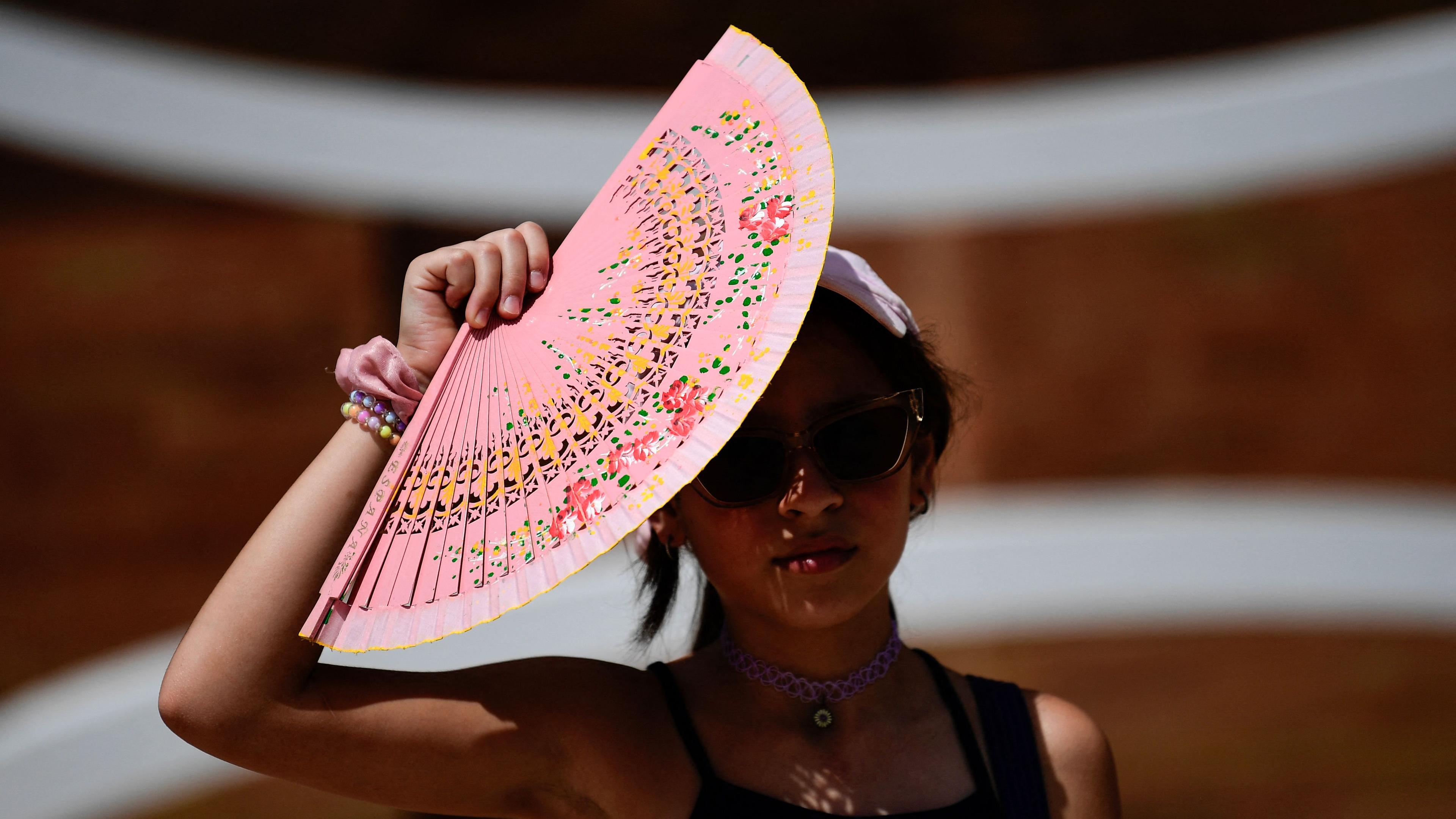 Eine Frau schützt sich mit einem Fächer vor der Sonne in Sevilla, Spanien.
