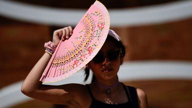 Eine Frau schützt sich mit einem Fächer vor der Sonne in Sevilla, Spanien.