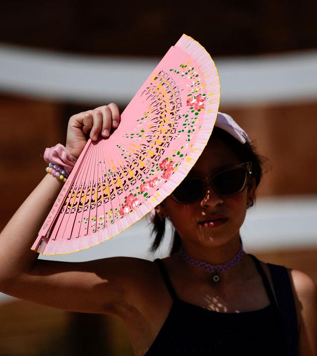 Eine Frau schützt sich mit einem Fächer vor der Sonne in Sevilla, Spanien.