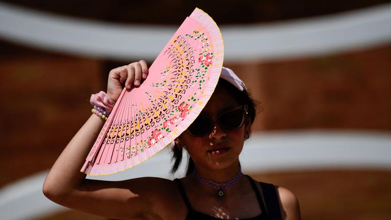 Eine Frau schützt sich mit einem Fächer vor der Sonne in Sevilla, Spanien.