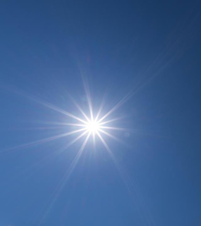 Die Sonne scheint vor blauem Himmel.